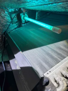 A high-output germicidal UVC air purifier lamp installed directly over an indoor HVAC evaporator coil in a Fort Myers residential home by Elevate Home Services.